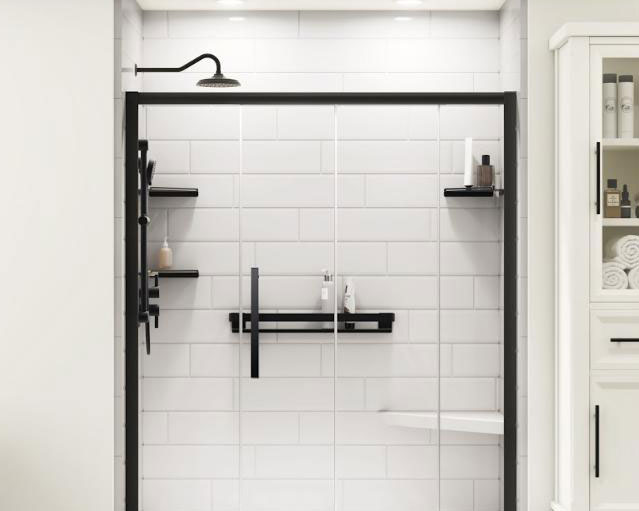 A close-up of a contemporary shower with matte black fixtures, including a rainfall showerhead, handle, and shelving. The shower features white subway tiles with dark grout, creating a striking contrast. A built-in niche provides convenient storage for bath products. The shower is enclosed by a clear glass door with a black metal frame, highlighting the modern, clean design. A small section of a white cabinet with neatly arranged towels and toiletries is visible to the right, suggesting a well-organized and stylish bathroom space.