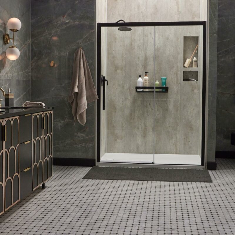 A modern bathroom with grey marble walls, a black vanity with gold accents, a glass-walled shower, hexagonal floor tiles, and stylish lighting fixtures.